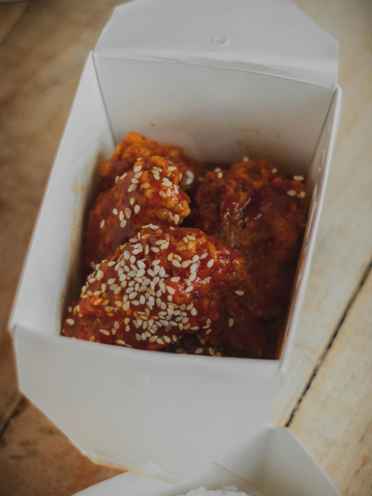 Korean yangnyeom fried chicken in a delivery box with sesame seeds