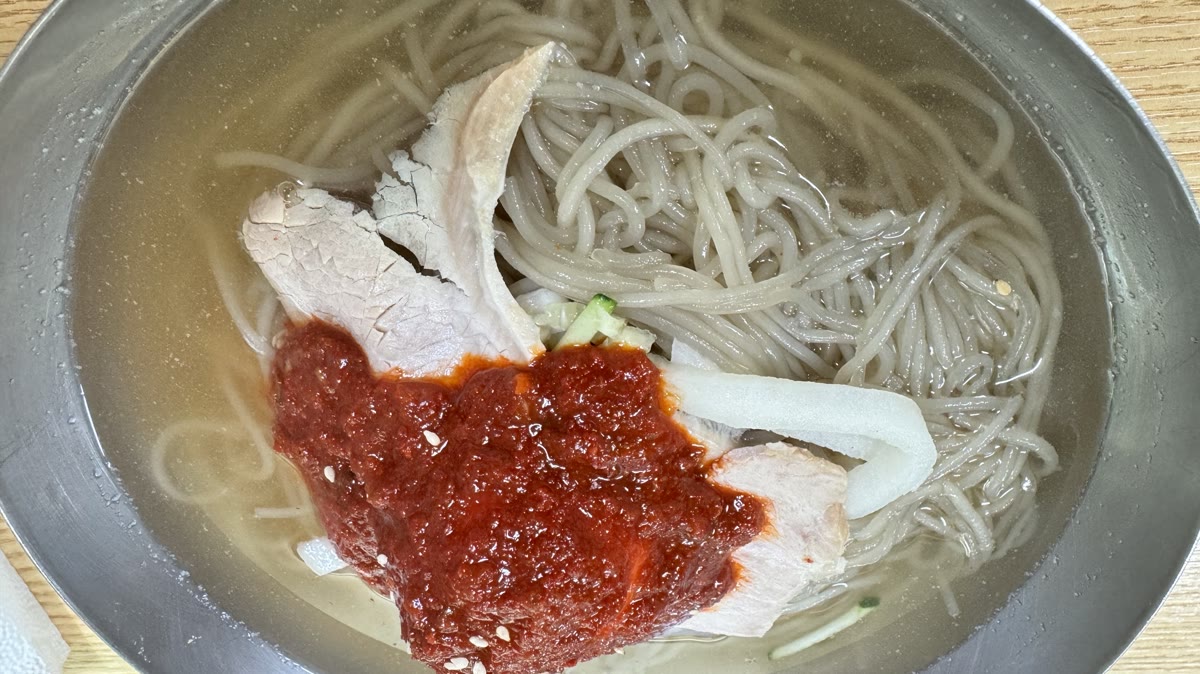釜山のミルミョン — 冷たいスープの上に辛いコチュジャンをのせた薄い小麦粉の麺